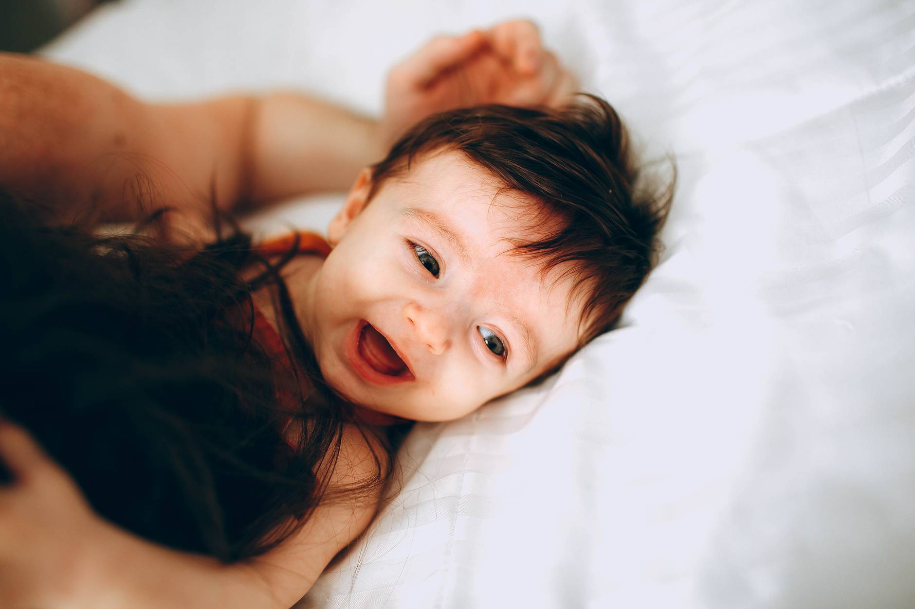 happy infant playing with parent in bed